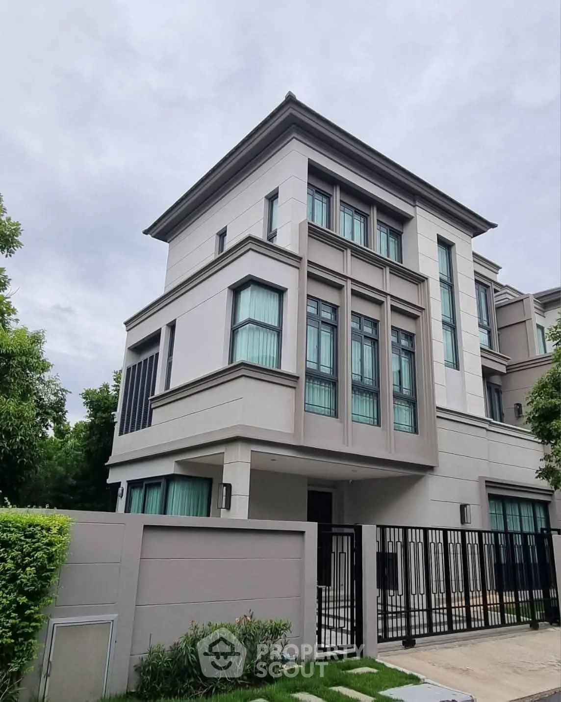 Modern three-story residential building with sleek design and gated entrance.