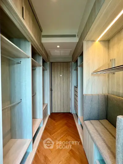Spacious walk-in closet with wooden shelves and seating area