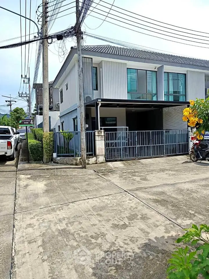Modern two-story house with gated entrance and driveway in a suburban neighborhood.