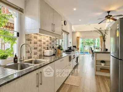 Spacious modern kitchen with open layout and garden view, featuring sleek appliances and elegant decor.