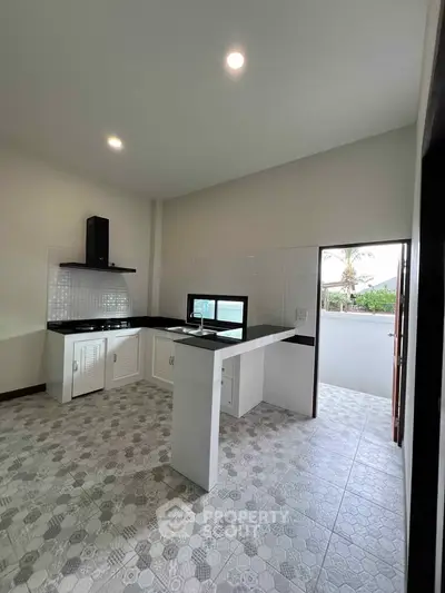 Modern kitchen with open layout and sleek design, featuring tiled flooring and outdoor access.
