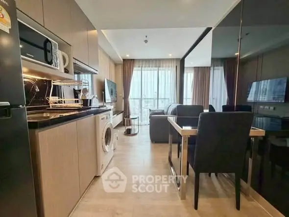 Modern open-layout living room with kitchen, featuring sleek appliances and stylish decor.