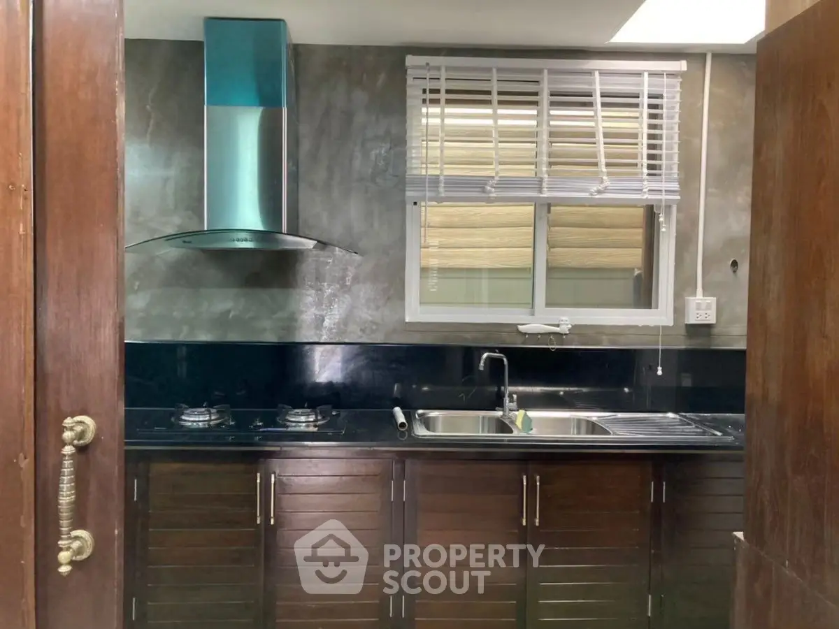 Modern kitchen with sleek cabinetry and gas stove, featuring a stylish range hood and ample natural light.