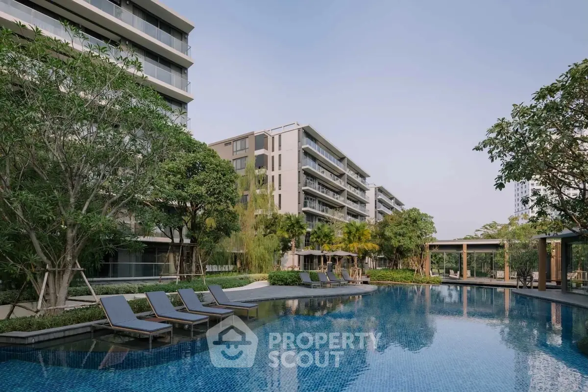 Luxurious residential complex with serene pool and lush greenery, offering a tranquil urban oasis.