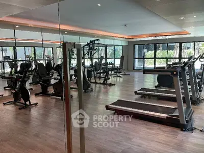 Spacious modern gym with state-of-the-art equipment and large windows for natural light.