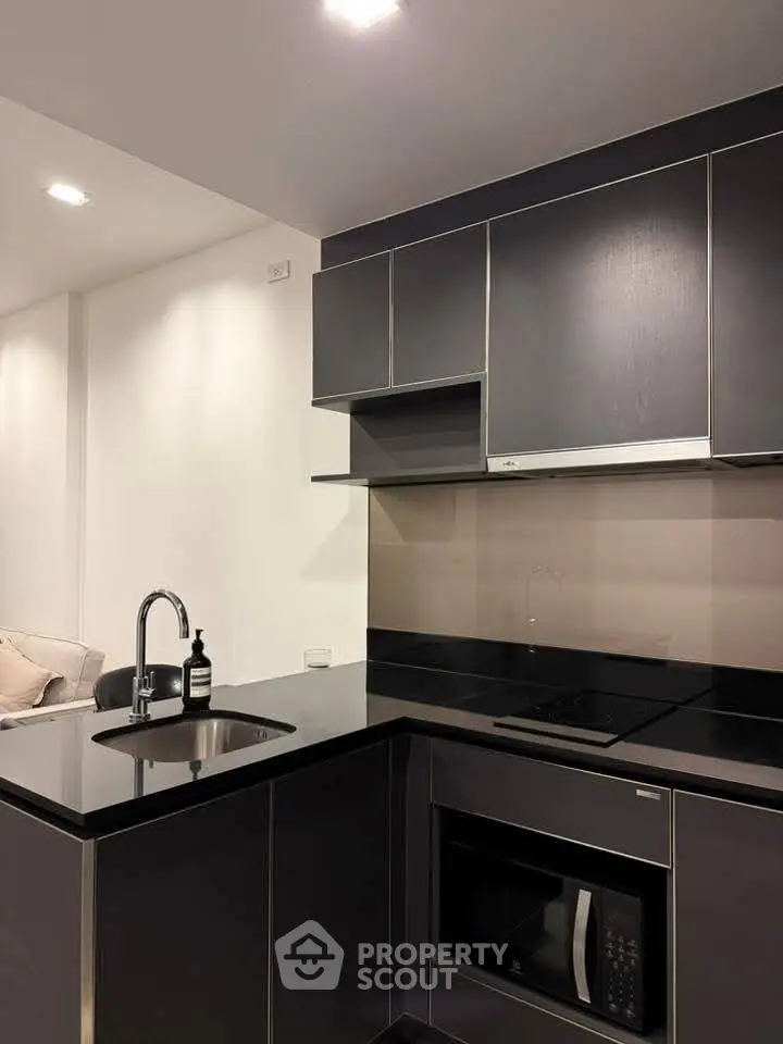 Modern kitchen with sleek black cabinetry and built-in appliances, perfect for contemporary living.