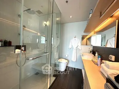 Luxurious modern bathroom with glass shower and elegant vanity lighting.