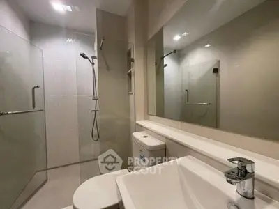Modern bathroom with sleek fixtures and glass shower enclosure.