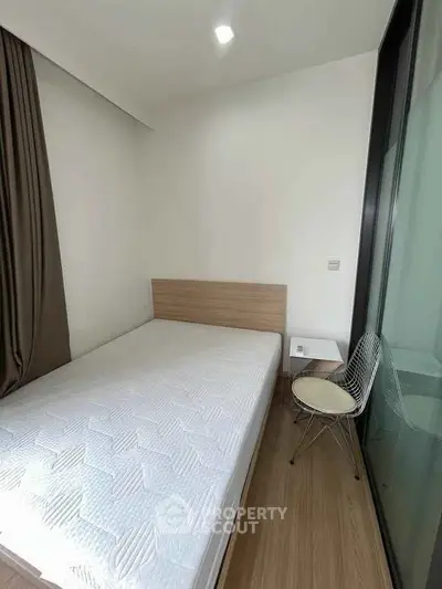 Cozy bedroom with modern design, featuring a comfortable bed and stylish chair by the window.