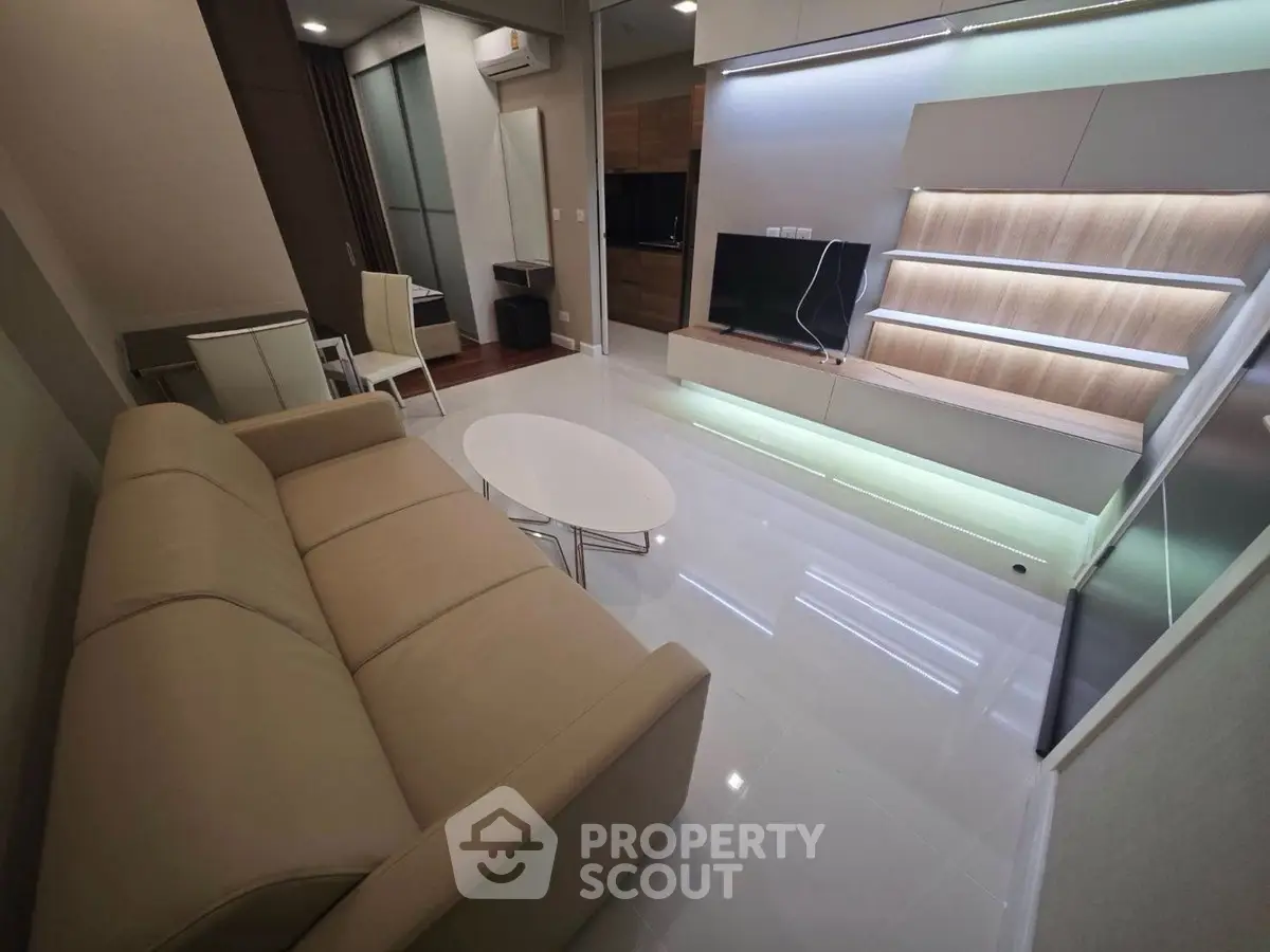 Modern living room with sleek design, featuring a beige sofa, glossy floors, and stylish shelving unit.