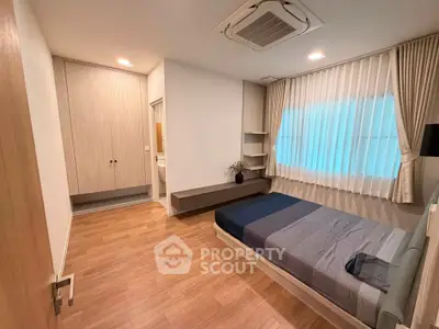 Modern bedroom with wooden flooring, built-in wardrobe, and cozy bed setup.