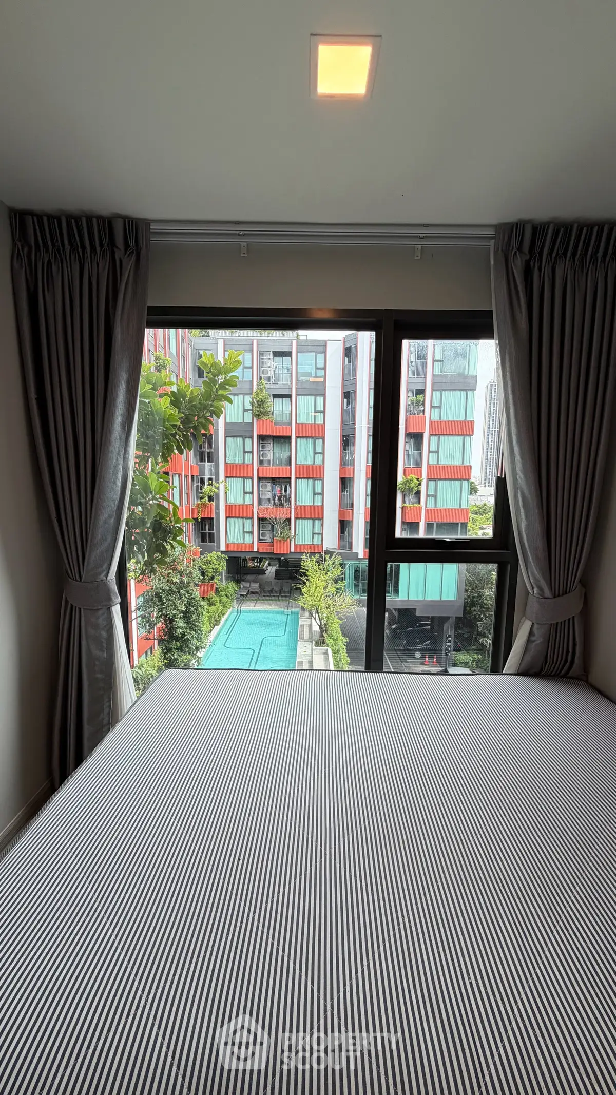 Modern bedroom with pool view in vibrant urban apartment complex