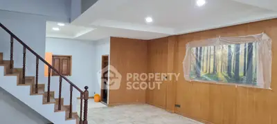 Spacious living room with wooden accents and staircase, perfect for modern living.