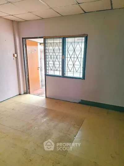 Spacious room with tiled floor and window, ideal for customization in a residential property.