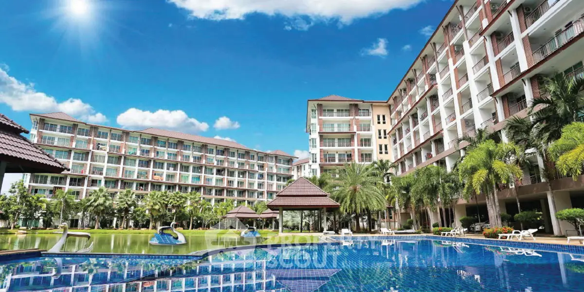 Luxurious condominium with stunning pool and lush landscaping under a bright blue sky.