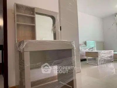 Modern bedroom with new furniture wrapped in protective plastic, showcasing a clean and spacious interior.