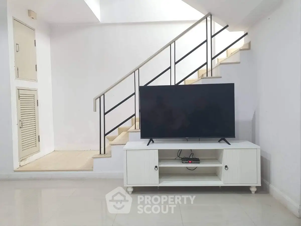 Modern living room with sleek staircase and TV unit, perfect for contemporary living.