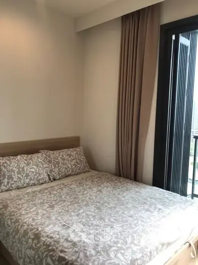 Cozy bedroom with elegant bedding and balcony view in modern apartment.