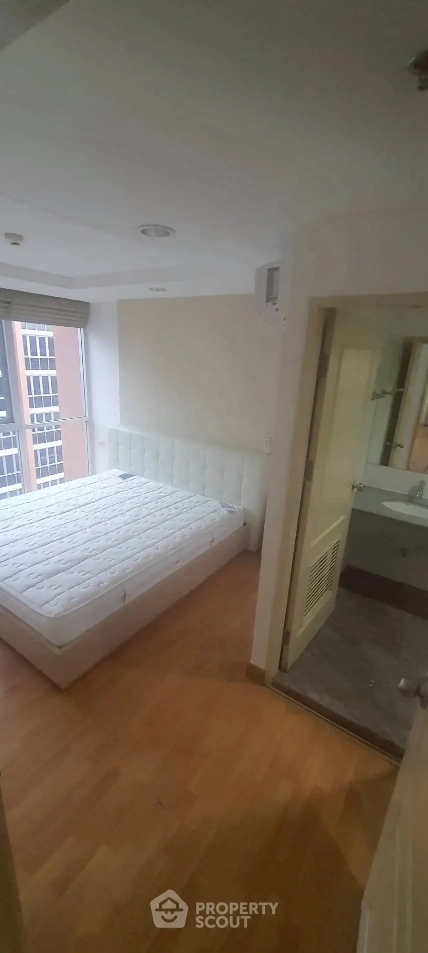 Cozy bedroom with large window and ensuite bathroom in modern apartment