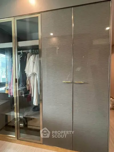 Elegant modern wardrobe with glass doors in a stylish bedroom setting.