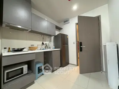 Modern kitchen with sleek cabinetry and appliances, featuring a microwave and refrigerator.