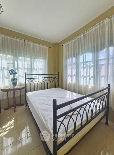 Bright and airy bedroom with large windows and elegant metal bed frame