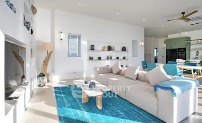 Spacious modern living room with elegant decor and open kitchen layout, featuring a cozy sofa and vibrant blue accents.