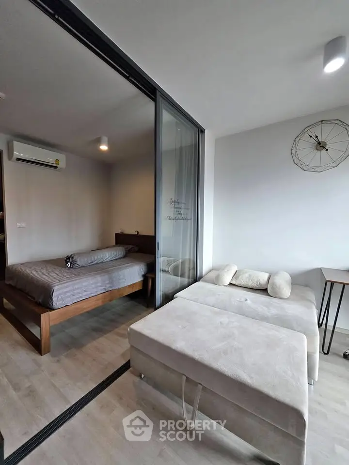 Modern apartment with sliding glass partition, cozy bedroom, and stylish living area.