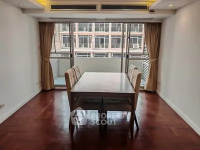 Spacious dining area with elegant wooden flooring and large windows in modern apartment.