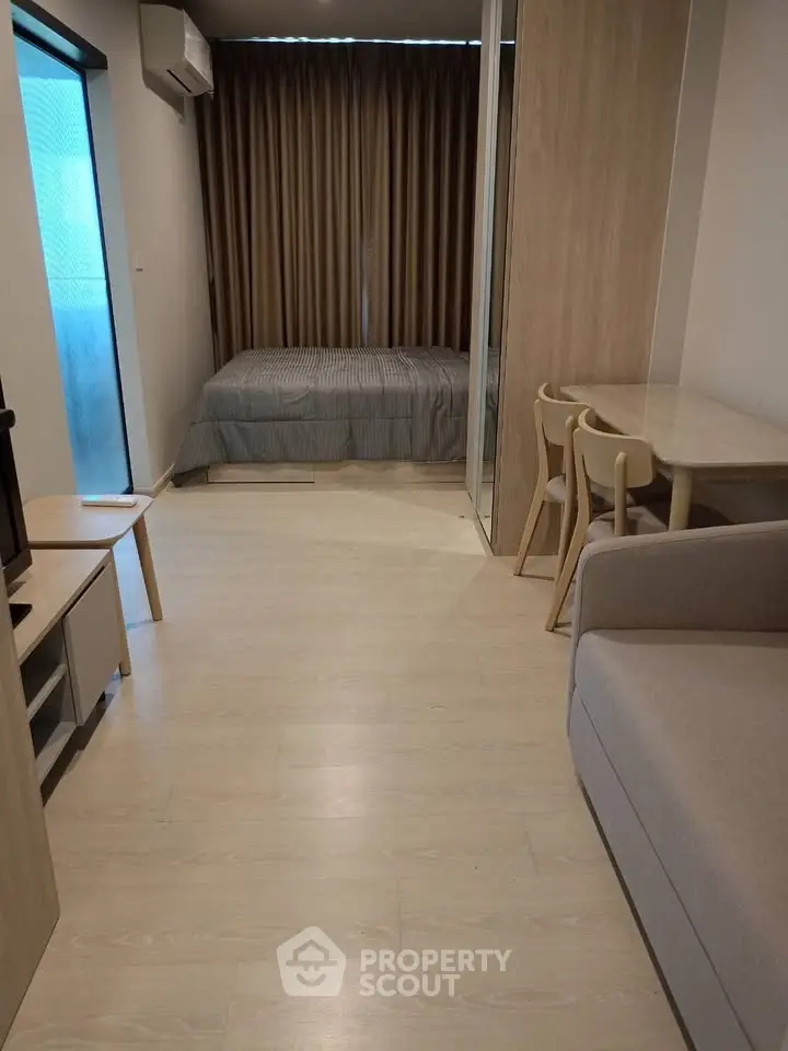 Modern studio apartment with cozy bedroom and stylish living area, featuring sleek wooden flooring and contemporary furniture.