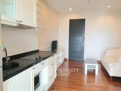 Charming living room with sleek kitchenette, cozy seating, and elegant wooden flooring.