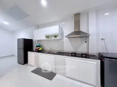 Modern kitchen with sleek white cabinets and stainless steel appliances, featuring a gas stove and spacious layout.
