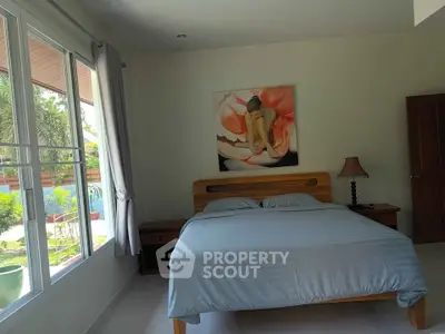 Cozy bedroom with large window and garden view, featuring elegant decor and natural light.