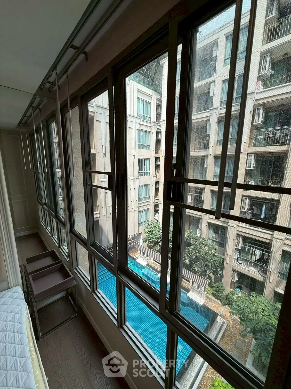 Spacious apartment with large windows overlooking a pool and modern building exterior.