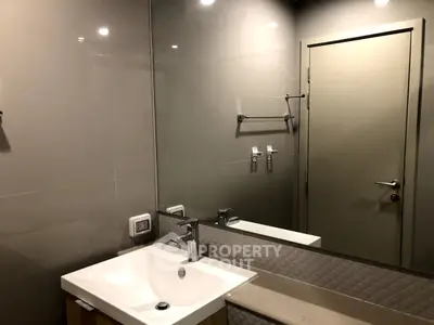 Modern bathroom with sleek sink and large mirror in contemporary design.