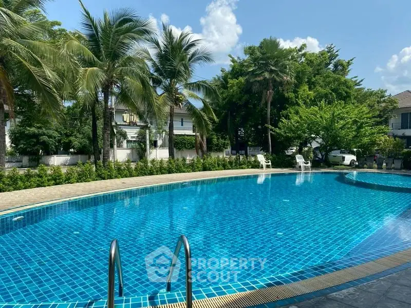 Luxurious outdoor pool surrounded by lush greenery in a serene residential area.