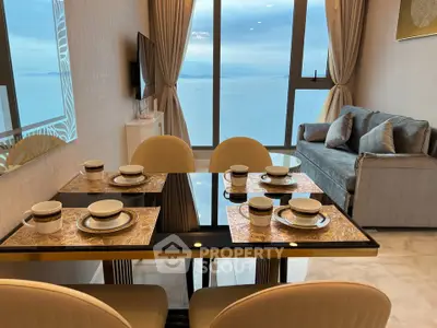Luxurious living room with ocean view, elegant dining setup, and modern decor in high-rise apartment.