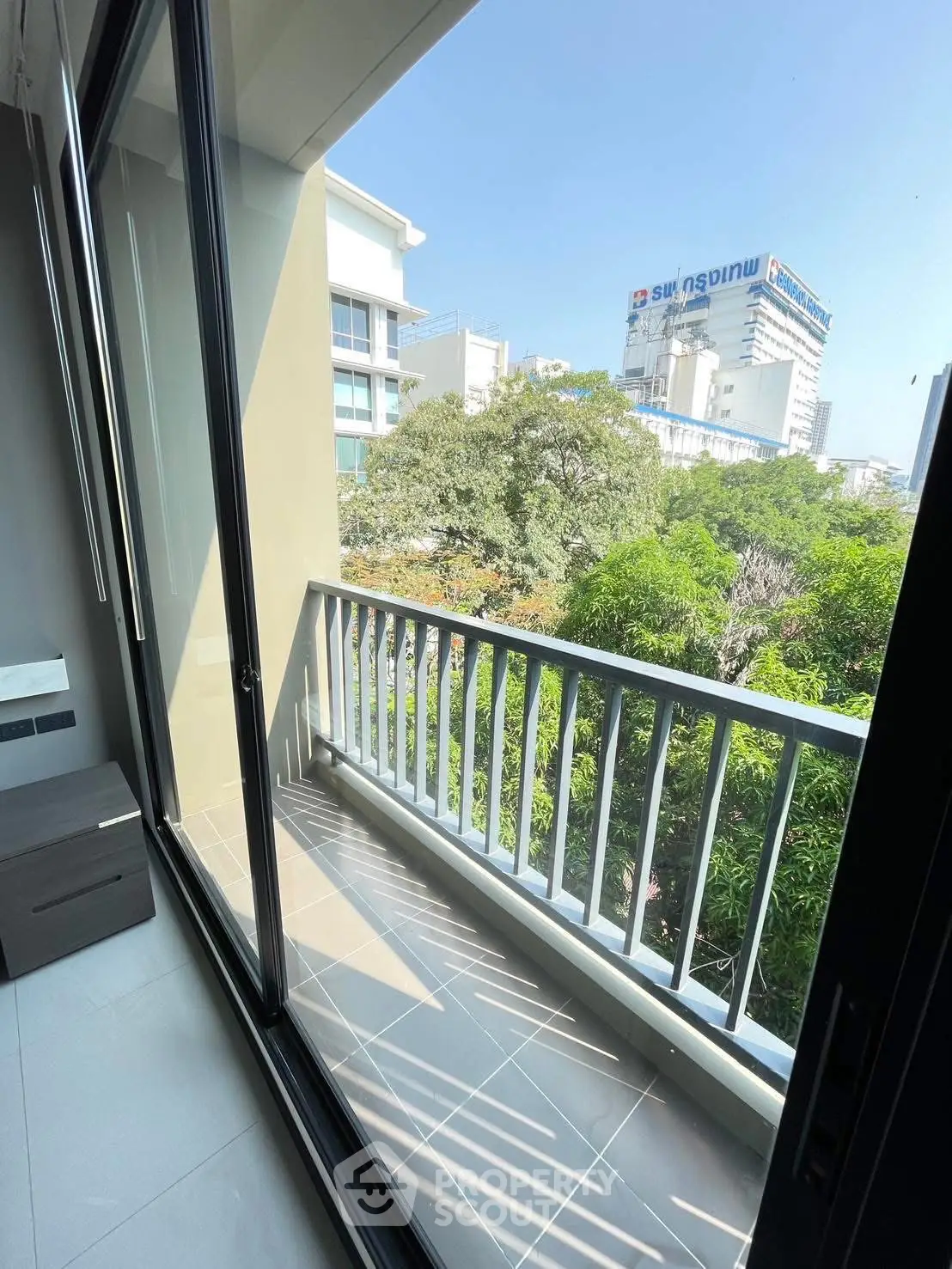Modern apartment balcony with city view and lush greenery
