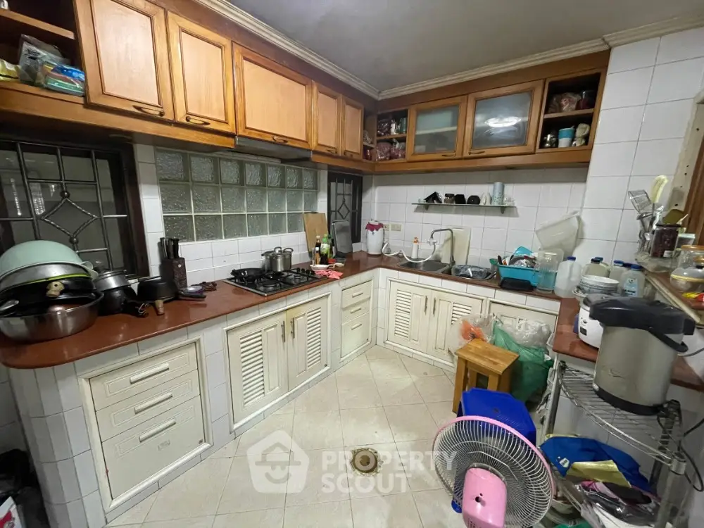Cozy kitchen with wooden cabinets and gas stove, featuring a compact layout and tiled flooring.