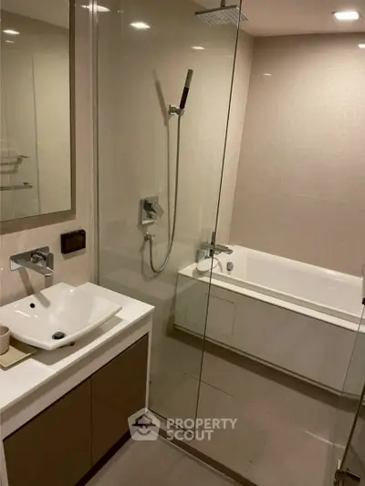 Modern bathroom with glass shower and bathtub in sleek design.