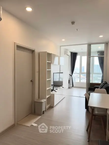 Modern living room with sleek furniture and large windows offering city views.