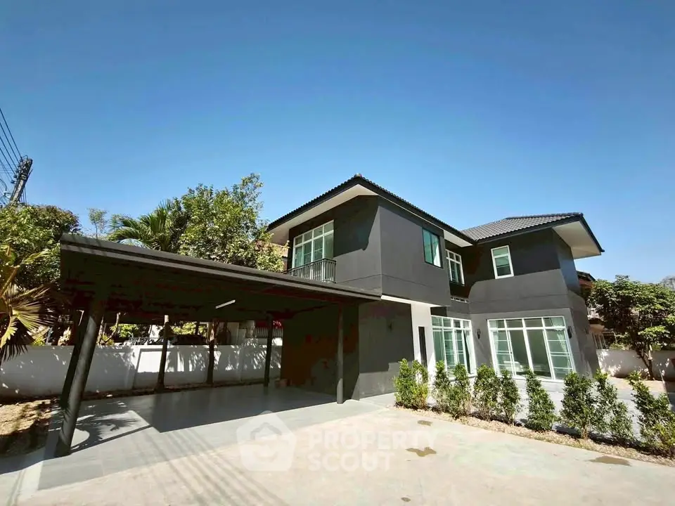 Modern two-story house with sleek design and spacious driveway under clear blue sky.