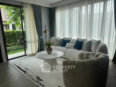 Elegant living room with modern sofa, large windows, and garden view