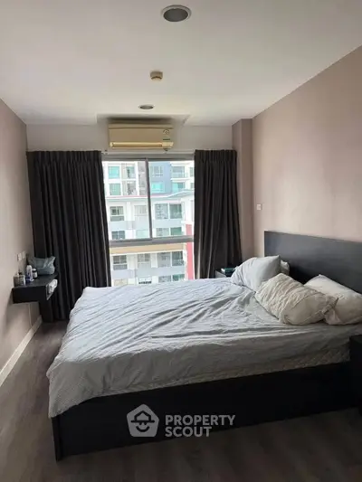 Spacious bedroom with large window offering city view, modern furnishings, and ample natural light.