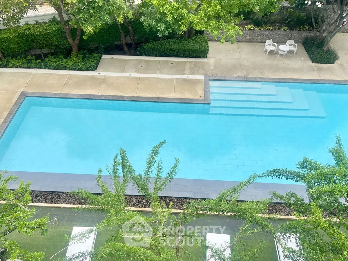 Luxurious outdoor pool with lush greenery and seating area, perfect for relaxation and leisure.