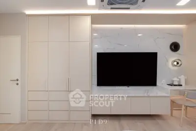 Modern living room with sleek cabinetry and large wall-mounted TV, featuring elegant marble accents.