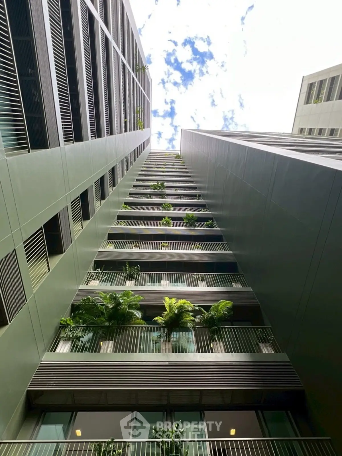 Modern high-rise building with lush green balconies and sleek architectural design.