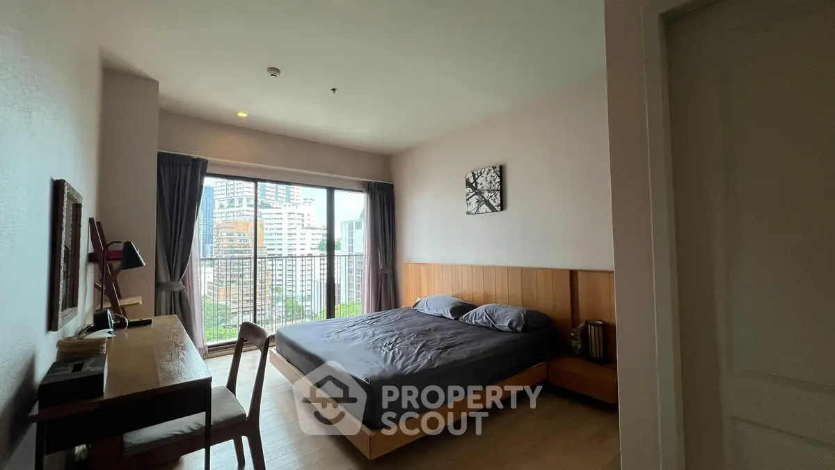 Modern bedroom with city view, featuring a stylish wooden bed and work desk, perfect for urban living.