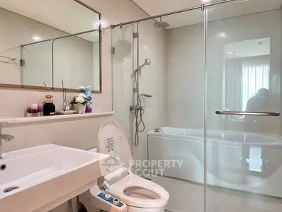 Modern bathroom with glass shower and sleek fixtures in luxury apartment.