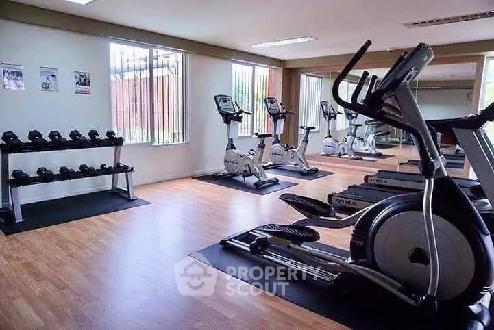 Spacious modern gym with exercise bikes and weights in a well-lit fitness area.